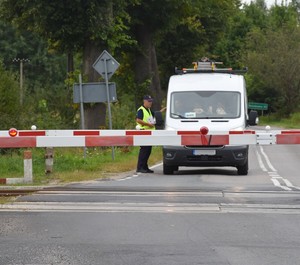 Funkcjonariusz Służby Ochrony Kolei wręcza kierowcom ulotki informacyjne.