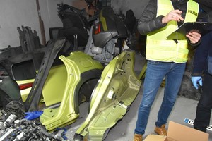 Policjant prowadzi oględziny wewnątrz garażu.