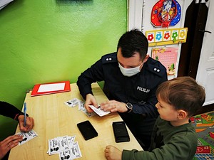 Policjant prezentuje dzieciom w jaki sposób pobiera się odciski palców.