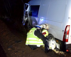 Policjant prowadzi oględziny ciężarowego renault. Auto stoi na poboczu drogi w rowie.
