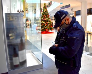 Policjant w galerii wypisuje mandat karny.