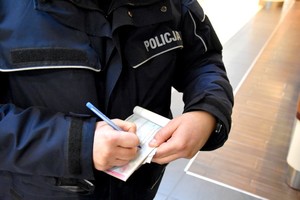 Umundurowany policjant wypisuje mandat.