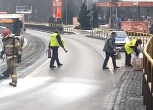 Policjanci wynoszą z auta przedmioty, które w wyniku akcji gaśniczej mogłyby uleć zniszczeniu.