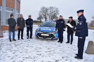 Widok ogólny na wszystkich uczestników uroczystości. W tle nowy radiowóz.