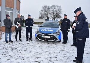 Widok ogólny na wszystkich uczestników uroczystości. W tle nowy radiowóz.