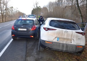 Na pierwszym planie widać tył odzyskanej mazdy, a po lewej stronie nieoznakowany radiowóz, który blokuje możliwość ucieczki. W pobliżu tych aut widoczny jest umundurowany policjant.