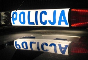 Nocne zdjęcie policyjnego koguta na dachu radiowozu z podświetlonym napisem o treści Policja.