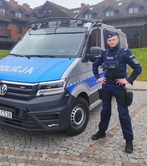 Policjant, który zatrzymał nietrzeźwego kierowcę stoi przy radiowozie.