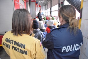 Strażacy, policjanci i uczniowie w hali garażowej w czasie pogadanki.