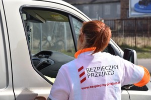 Pracownica PKP wręcza ulotkę kierowcy.