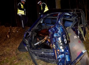 Na pierwszym planie tył uszkodzonego audi. W oddali policjanci z drogówki, którzy prowadzą oględziny miejsca zdarzenia.