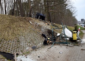 Na pierwszym planie zdewastowana wiata przystankowa. W oddali na skarpie widać rozbite audi.