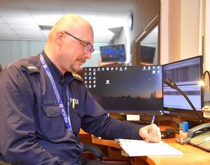 Aspirant sztabowy Mariusz Stosik siedzi za biurkiem na stanowisku zastępcy dyżurnego Komendy Powiatowej Policji w Starogardzie Gdańskim.