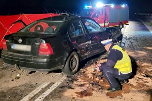 Policjant prowadzi oględziny rozbitego pojazdu.