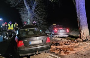 Na pierwszym planie tył rozbitego volkswagena. Za pojazdem widoczne służby pracujące na miejscu zdarzenia.