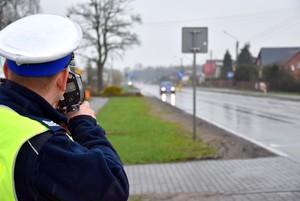 Policjant z radarem mierzy prędkość pojazdu.