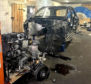 Karoseria całkowicie rozkręconego mercedesa stojąca w garażu. Widok z przodu.