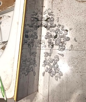 Zawiniątka foli aluminiowej z suszem roślinnym leżące na podłodze w łazience.