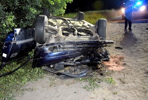 Noc. Drzewo oraz leżący w pobliżu niego na dachu rozbity opel.
