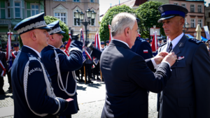 Marszałek Województwa Pomorskiego odznacza medalem funkcjonariusza Policji. Tuż za nim stoi Komendant Główny Policji oraz Komendant Wojewódzki Policji w Gdańsku.