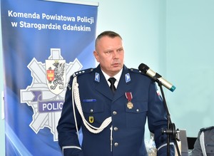 Pierwszy Zastępca Komendanta Wojewódzkiego Policji w Gdańsku przemawia do uczestników uroczystości. Policjant stoi przy mównicy, przed mikrofonem.