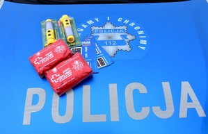 Maska policyjnego radiowozu z napisem Policja oraz chronimy i pomagamy. Ma masce leżą rozdawane przez funkcjonariuszy apteczki i latarki.