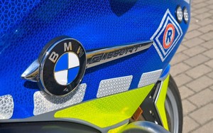 Prawy bok motocykla. Widoczne nowe malowanie pojazdu służbowego w dotychczasowych barwach policyjnych wzbogaconych o jaskrawożółty kolor. Widoczny znaczek firmowy marki BMW oraz literka R - oznakowanie służby ruchu drogowego.