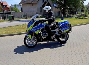 Policjant jedzie na motocyklu. Widok jego lewego boku.