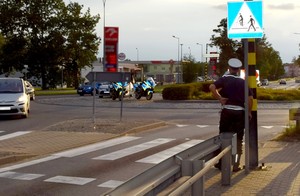 Policjanci na miejscu zdarzenia prowadzą czynności procesowe. W oddali widać policyjne motocykle.
