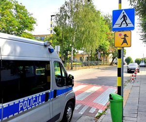 Radiowóz przejeżdża przez przejście dla pieszych. Po prawej stronie słup ze znakami &quot; Przejście dla pieszych&quot; i &quot;Agatka&quot;.