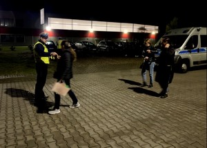 Policjanci wręczają przybywającym do pracy pracownikom elementy odblaskowe.