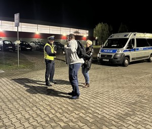 Policjanci wręczają przybywającym do pracy pracownikom elementy odblaskowe.