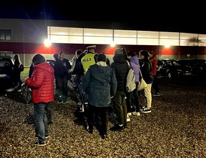 Policjanci wręczają przybywającym do pracy pracownikom elementy odblaskowe.