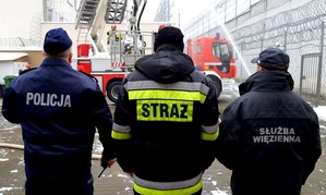 Od lewej: policjant, strażak i funkcjonariusz aresztu śledczego - nadzorują przeprowadzane w trakcie ćwiczeń czynności.