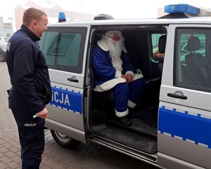 Niebieski Mikołaj siedzi na tylnym siedzeniu policyjnego volkswagena.