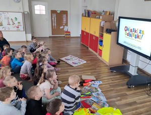 Dzieci siedzą przed telewizorem i oglądają kreskówkę pt. Trefliki.