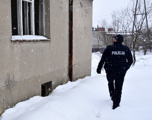 Policjant sprawdza pustostany, poszukując w nich osób bezdomnych wymagających pomocy.