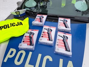 Maska radiowozu policyjnego, a na niej żółta kamizelka odblaskowa oraz uniwersalne zbijaki do szyb, które policjanci rozdają w czasie prowadzonych działań.