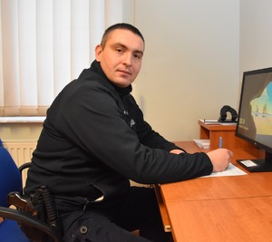 Policjant sporządza dokumentację przy biurku w komendzie.
