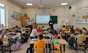 Policjantka stojąca przy tablicy prowadzi zajęcia z uczniami.