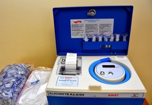 Nowy alkometr. Niebiesko siwa skrzynka z ustnikami do dmuchania, wyświetlaczem i niebieskim wężem.