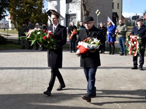 Delegacja składająca kwiaty przy tablicy upamiętniającej Zbigniewa Badochę.