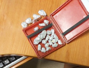 Zabezpieczone pudełko koloru czerwonego, w którym znajdują się zawiniątka folii aluminiowej z mefedronem.