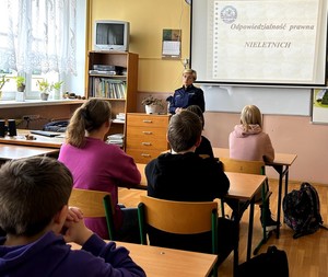 Policjantka w klasie szkolnej prowadzi zajęcia z uczniami.