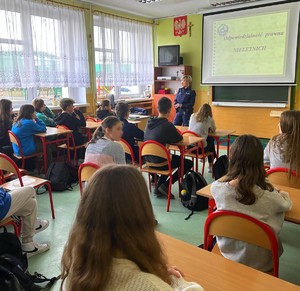 Policjantka w klasie szkolnej prowadzi zajęcia z uczniami.
