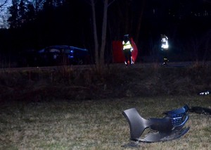 Porozrzucane na polu wzdłuż drogi elementy pojazdu. W oddali widać rozbitego opla, który uczestniczył w wypadku.