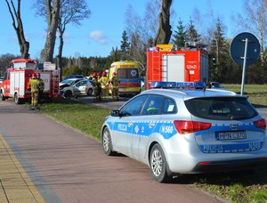 Na pierwszym planie policyjny radiowóz. W oddali widać służby ratownictwa drogowego, które pracują na miejscu zdarzenia.
