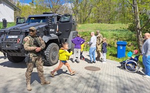 Na pierwszym planie policjant z oddziału kontr terrorystycznego, a za nim auto specjalistyczne Dżygit.