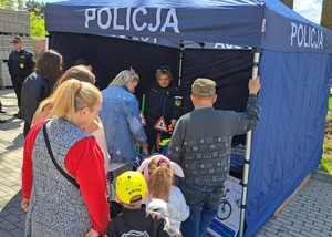 Policjantka w policyjnym namiocie rozmawia z dziećmi o bezpieczeństwie.