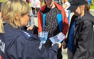 Policjantka rozdaje ulotki dotyczące doboru do służby.